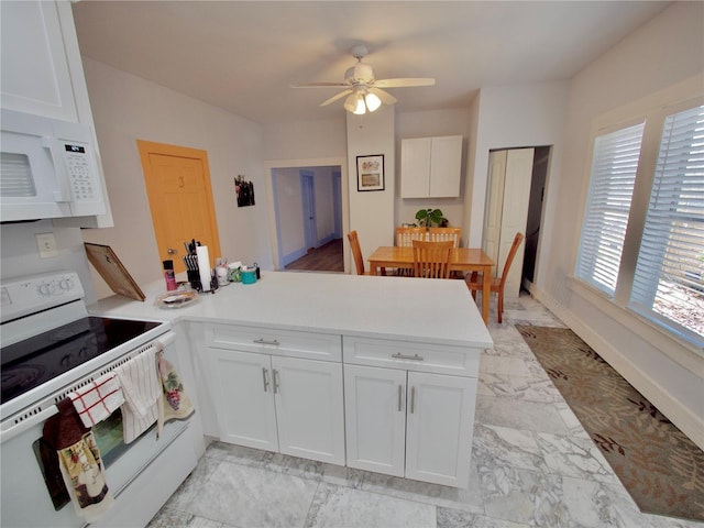 kitchen featuring white appliances, kitchen peninsula, and white cabinets