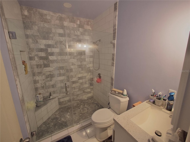 bathroom featuring vanity, toilet, a shower with door, and tile patterned flooring