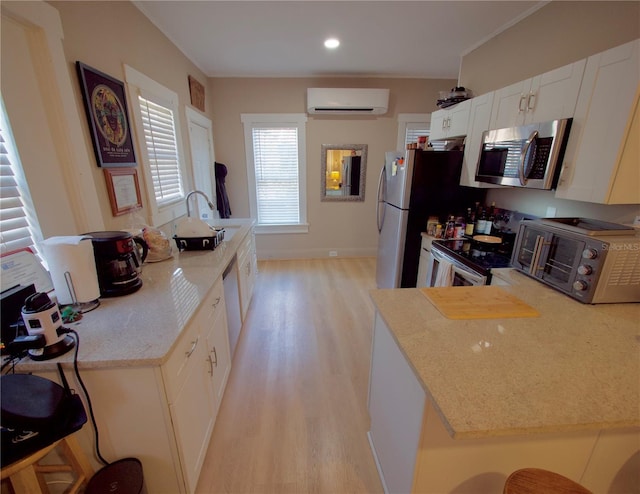 kitchen with appliances with stainless steel finishes, white cabinetry, a wall unit AC, a kitchen breakfast bar, and light wood-type flooring