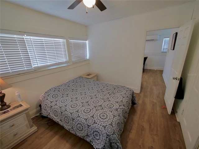 bedroom featuring ceiling fan, a wall mounted air conditioner, and hardwood / wood-style floors