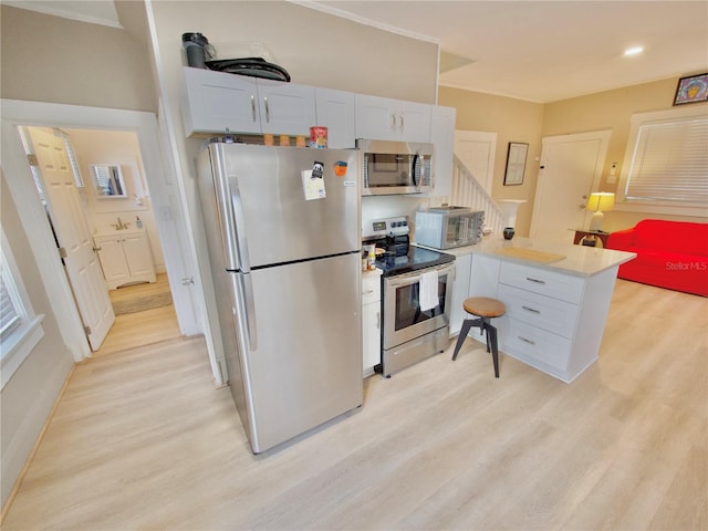 kitchen featuring stainless steel appliances, white cabinets, light wood-type flooring, and kitchen peninsula