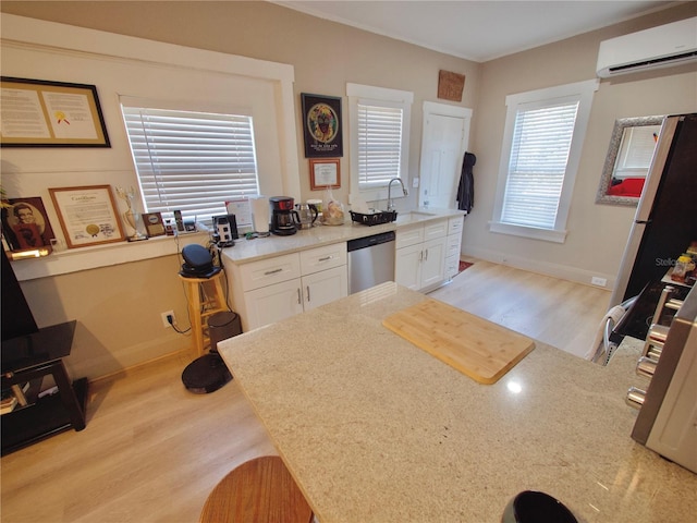 kitchen featuring sink, white cabinetry, light wood-type flooring, an AC wall unit, and stainless steel dishwasher