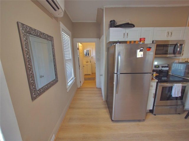 kitchen with white cabinetry, stainless steel appliances, light hardwood / wood-style flooring, and a wall mounted air conditioner