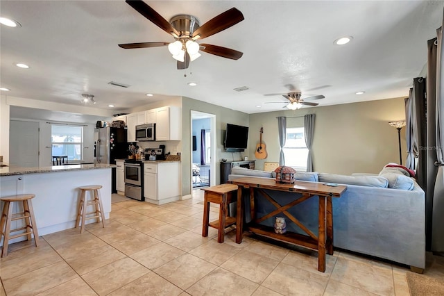 living room with light tile patterned flooring, ceiling fan, and a healthy amount of sunlight