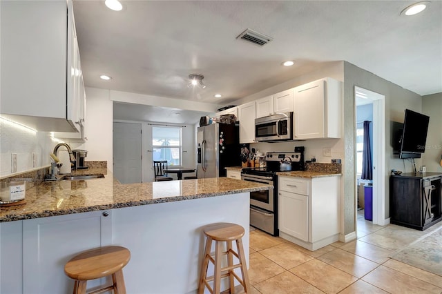 kitchen featuring sink, stainless steel appliances, a kitchen breakfast bar, and kitchen peninsula