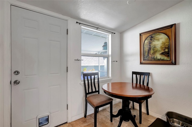 dining space with light tile patterned floors and vaulted ceiling