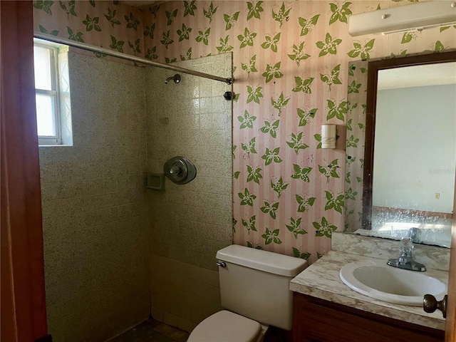 bathroom featuring vanity, a tile shower, and toilet