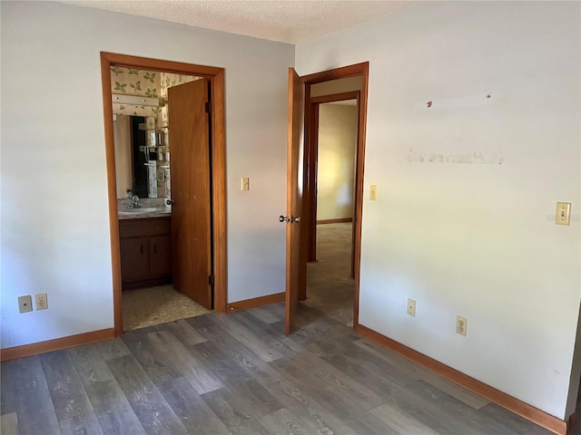 spare room featuring sink, dark wood-type flooring, and a textured ceiling