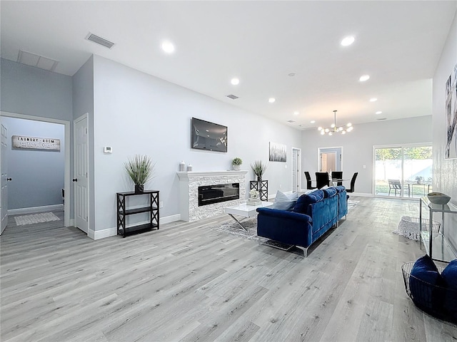 living room with an inviting chandelier, a fireplace, and light hardwood / wood-style floors