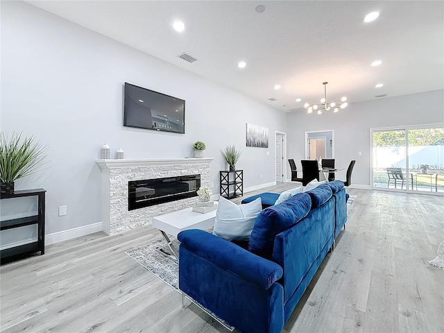 living room with a notable chandelier, a fireplace, and light hardwood / wood-style floors