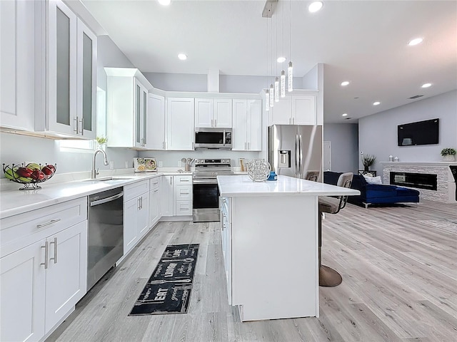 kitchen with pendant lighting, white cabinetry, sink, a kitchen bar, and stainless steel appliances