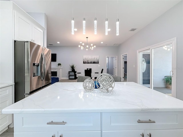 kitchen featuring a center island, stainless steel fridge, decorative light fixtures, and white cabinets