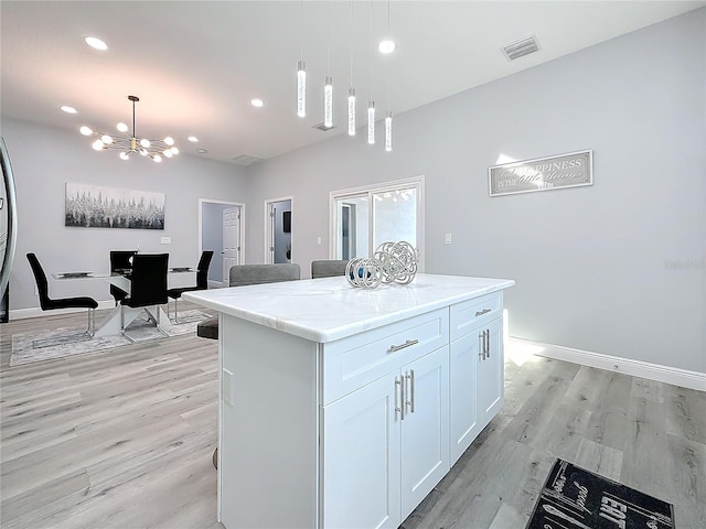 kitchen with white cabinetry, decorative light fixtures, light hardwood / wood-style floors, and a kitchen island