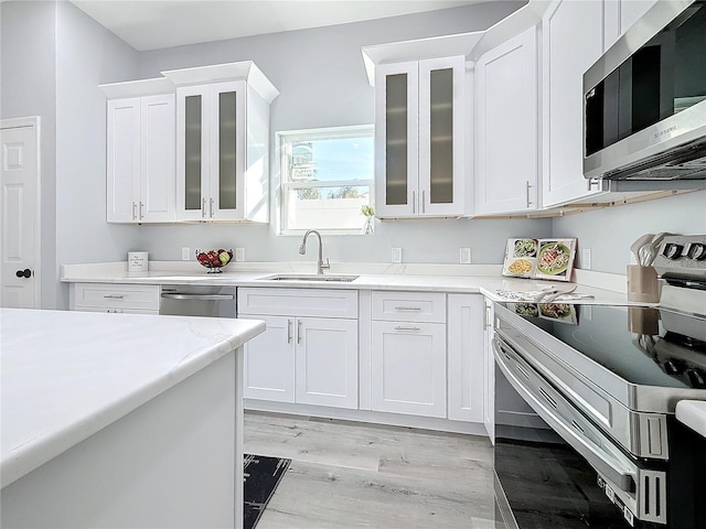 kitchen featuring sink, light wood-type flooring, white cabinets, and appliances with stainless steel finishes