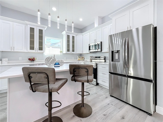 kitchen with pendant lighting, appliances with stainless steel finishes, a center island, and white cabinets