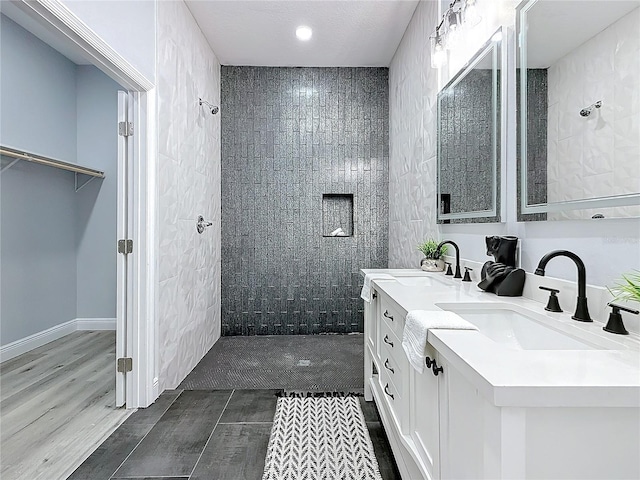 bathroom featuring tiled shower, vanity, and wood-type flooring