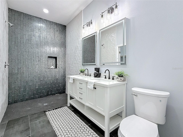 bathroom featuring vanity, a tile shower, and toilet