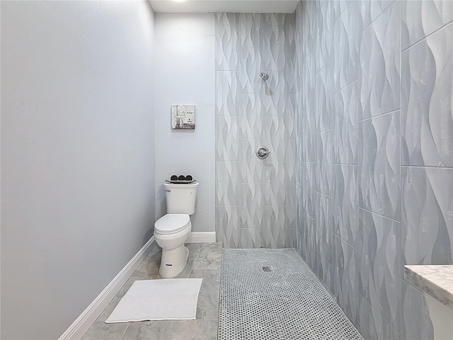 bathroom featuring tile patterned flooring, tiled shower, and toilet