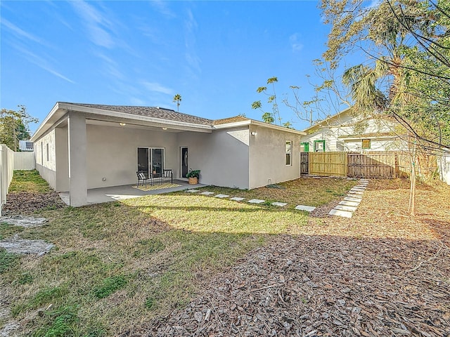 back of property with a yard and a patio