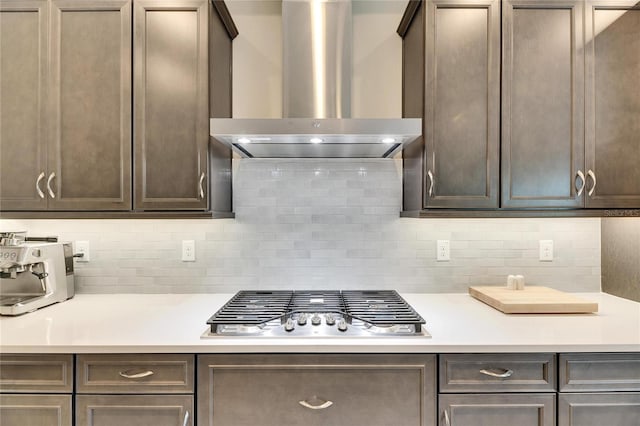 kitchen featuring tasteful backsplash, wall chimney range hood, dark brown cabinets, and stainless steel gas cooktop