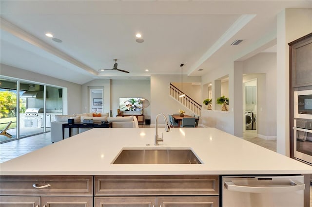 kitchen with sink, ceiling fan, stainless steel appliances, a center island with sink, and washer / clothes dryer