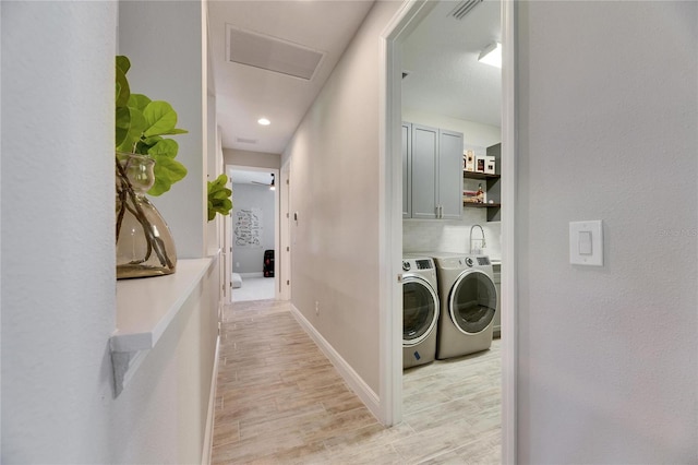 laundry room with cabinets, washing machine and dryer, and light hardwood / wood-style floors