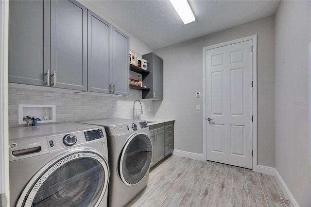 washroom featuring sink, cabinets, a textured ceiling, washer and dryer, and light wood-type flooring