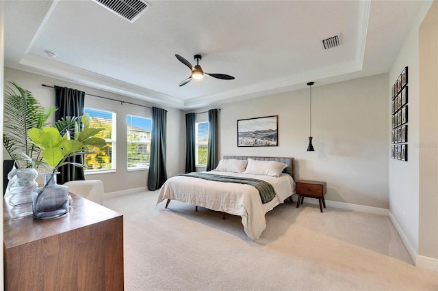 carpeted bedroom with a raised ceiling and ceiling fan