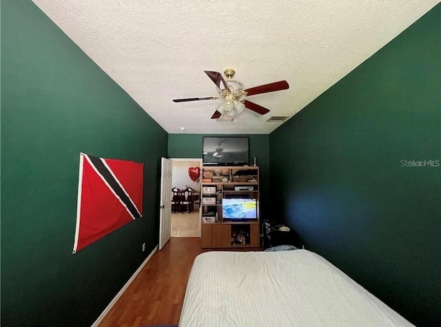 bedroom with hardwood / wood-style flooring, ceiling fan, and a textured ceiling