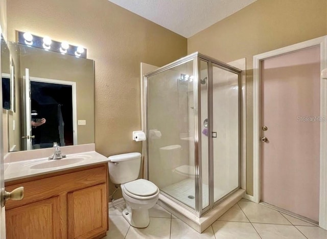 bathroom featuring tile patterned flooring, vanity, toilet, a shower with door, and a textured ceiling