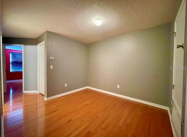 empty room featuring wood-type flooring and a textured ceiling