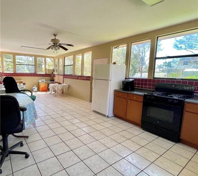 kitchen featuring black gas range, white fridge, and light tile patterned floors