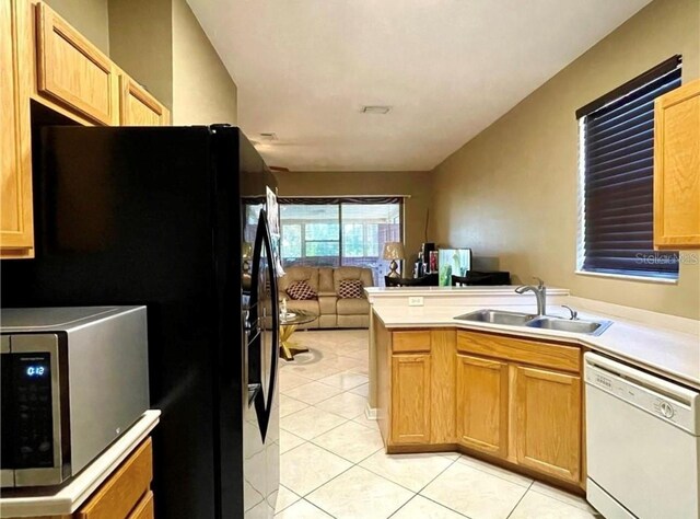 kitchen with light tile patterned flooring, sink, black fridge, dishwasher, and kitchen peninsula