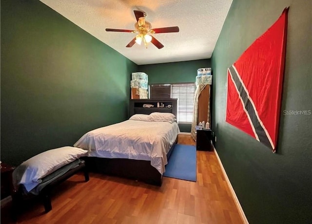 bedroom with ceiling fan, wood-type flooring, and a textured ceiling