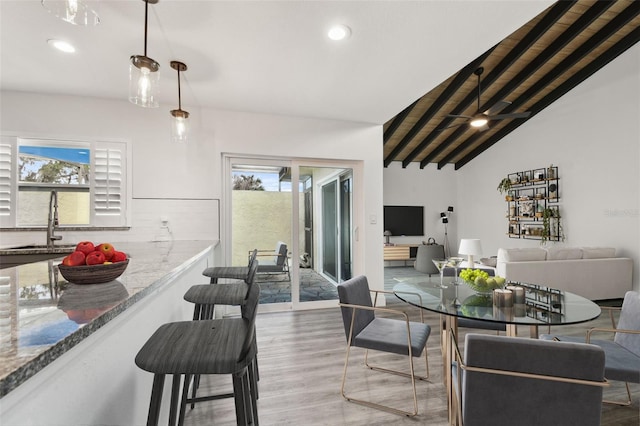 dining room with recessed lighting, plenty of natural light, lofted ceiling with beams, and wood finished floors