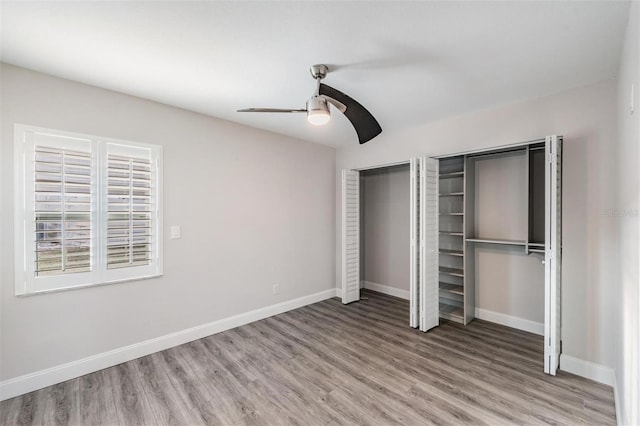 unfurnished bedroom featuring light wood-style flooring, baseboards, and two closets