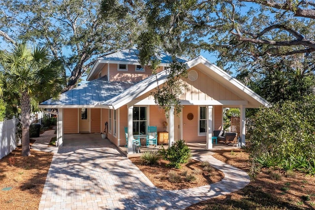 view of front of house featuring covered porch, fence, and decorative driveway