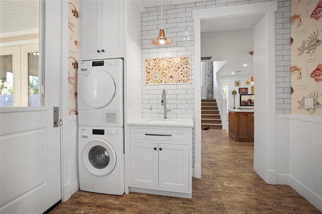 washroom with stacked washer / drying machine, dark hardwood / wood-style flooring, and sink