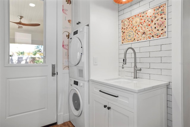 washroom featuring sink, cabinets, ceiling fan, and stacked washer / dryer