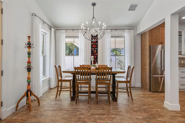 dining space with hardwood / wood-style flooring, vaulted ceiling, and a wealth of natural light