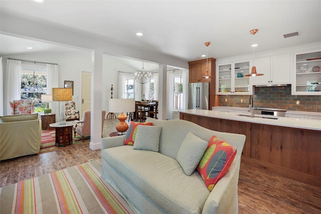 interior space featuring sink, white cabinetry, decorative light fixtures, stainless steel fridge, and backsplash