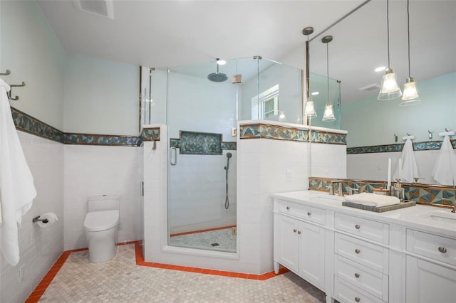 bathroom with a shower with door, tile patterned flooring, tile walls, vanity, and toilet