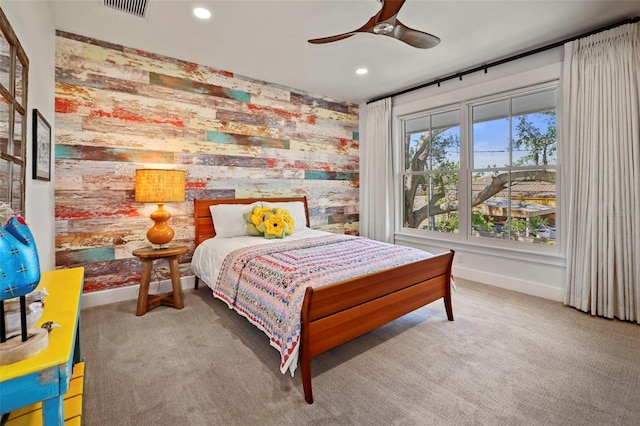 carpeted bedroom featuring ceiling fan and wood walls