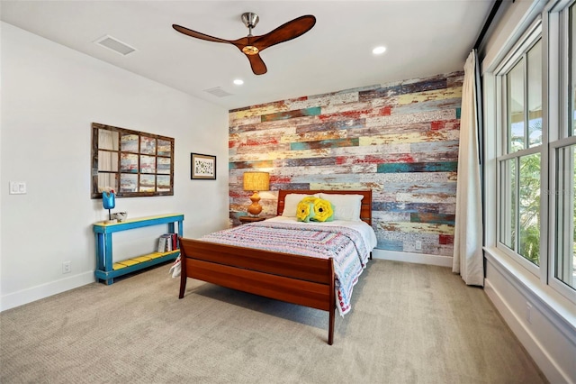 carpeted bedroom with ceiling fan and wood walls