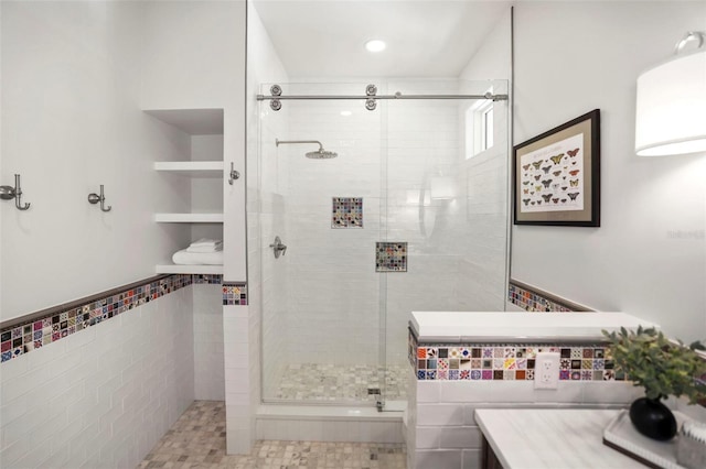 bathroom featuring wainscoting, a shower stall, and tile walls