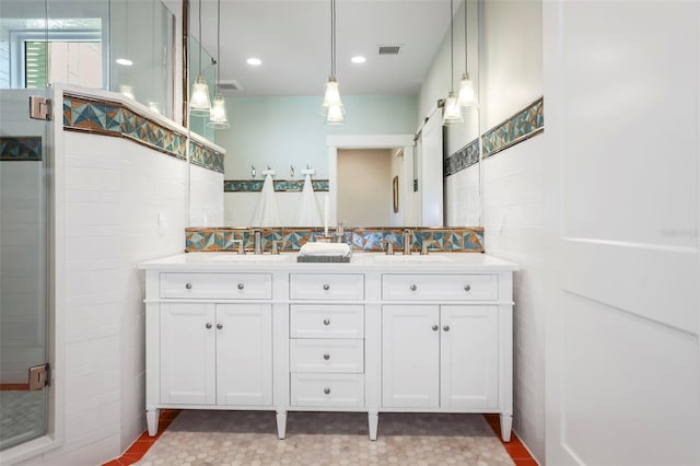 bathroom featuring double vanity, a shower stall, and a sink