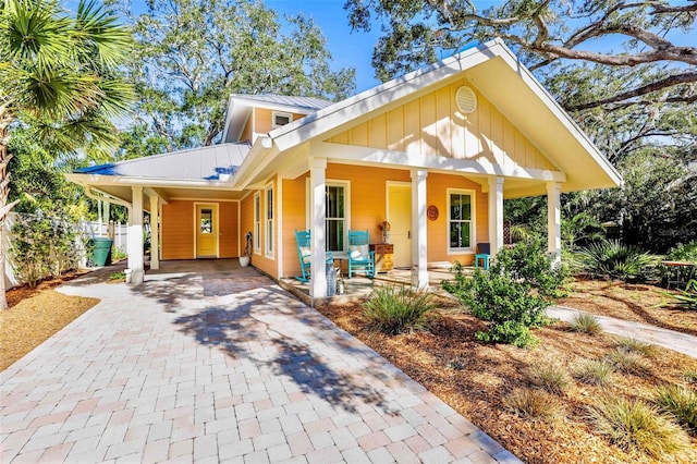 view of front of house with a carport, metal roof, a porch, and decorative driveway