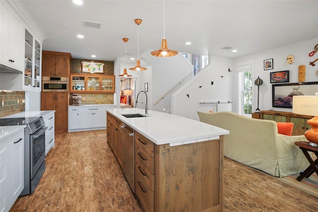 kitchen with sink, white cabinetry, stainless steel appliances, an island with sink, and decorative light fixtures