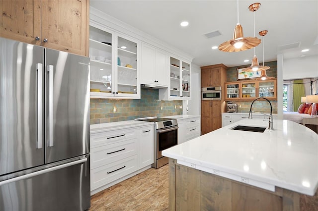 kitchen with stainless steel appliances, white cabinets, a sink, and decorative light fixtures