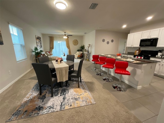 dining space featuring visible vents, ceiling fan, baseboards, and light tile patterned flooring